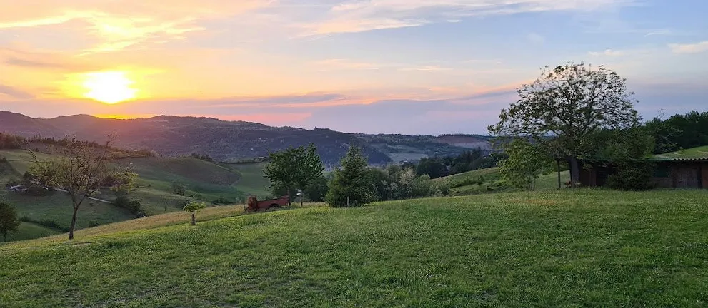 Il sole che tramonta dietro le colline della Val Nure, visto dal prato.